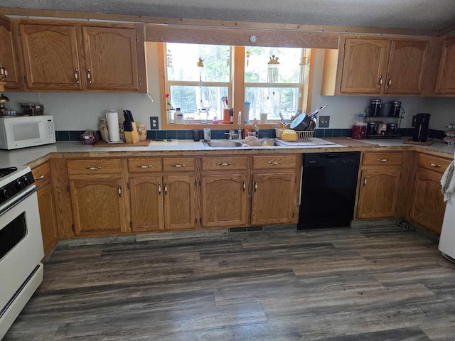 kitchen with visible vents, light countertops, dark wood-style floors, white appliances, and a sink