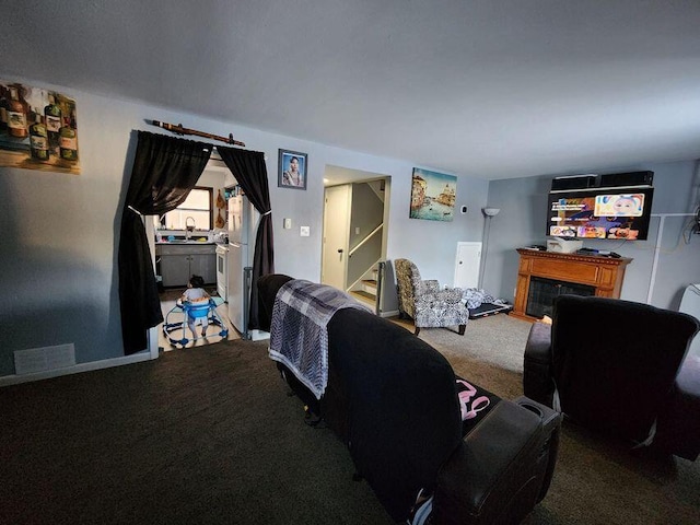 living area featuring a fireplace, stairs, carpet, and visible vents