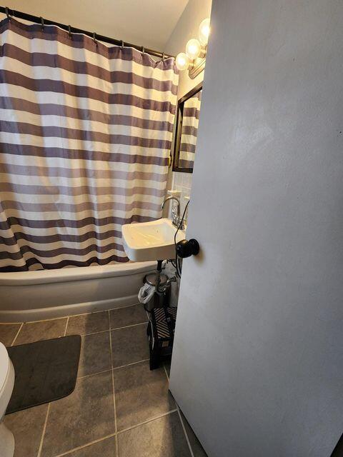 bathroom featuring tile patterned floors, shower / tub combo, toilet, and a sink