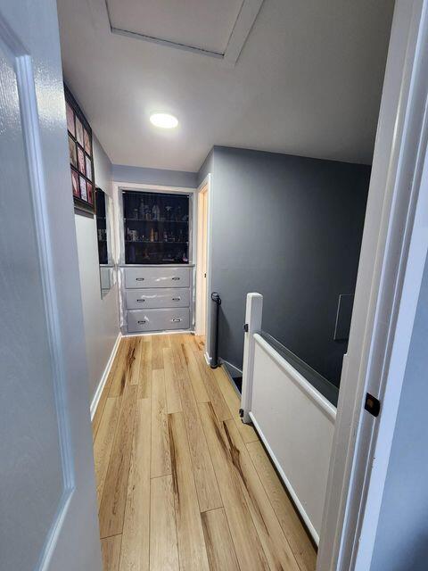 corridor featuring attic access, an upstairs landing, baseboards, and light wood finished floors