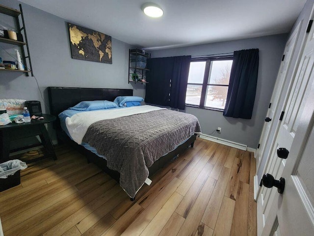 bedroom with baseboard heating, baseboards, and wood finished floors