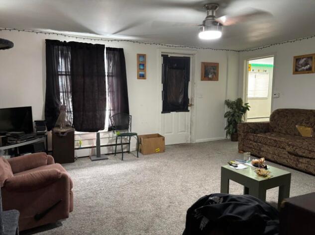 carpeted living area featuring ceiling fan and a baseboard radiator