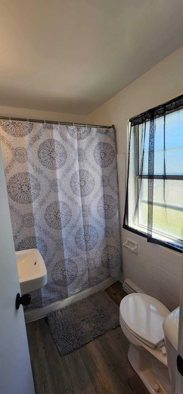 bathroom with curtained shower, toilet, tile walls, and wood finished floors