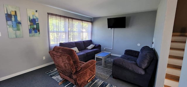 carpeted living area with stairs and baseboards