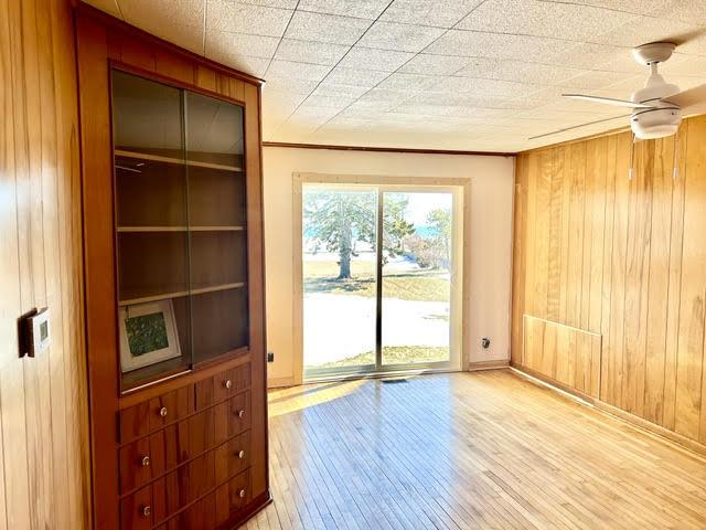 spare room with wooden walls, a ceiling fan, and hardwood / wood-style flooring