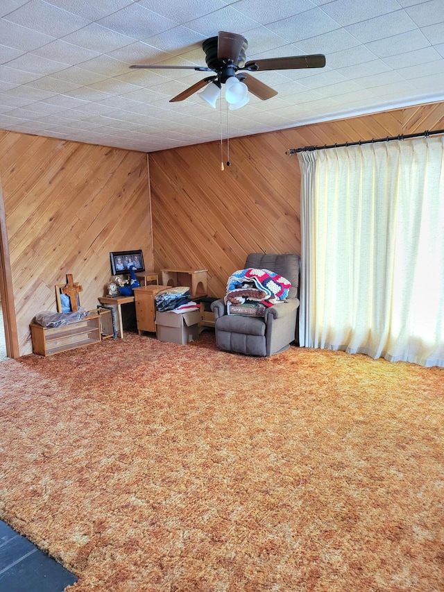 interior space with wooden walls, ceiling fan, and carpet flooring