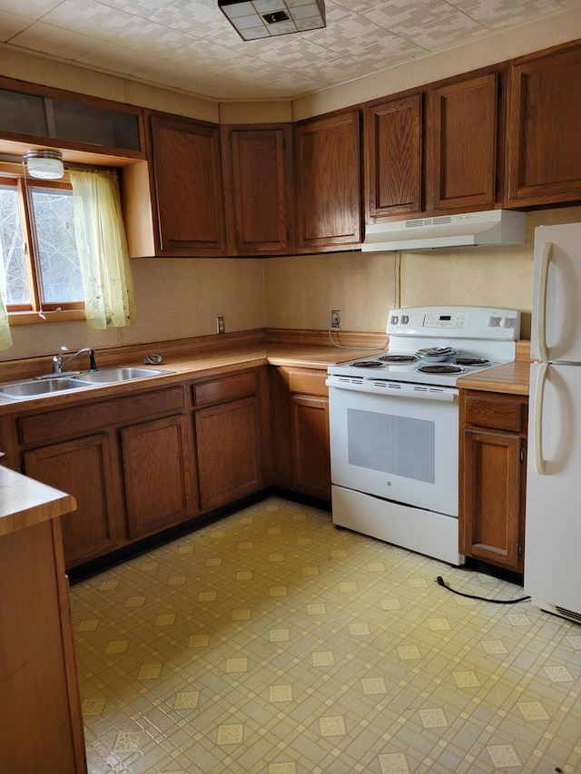 kitchen with visible vents, under cabinet range hood, brown cabinetry, white appliances, and a sink