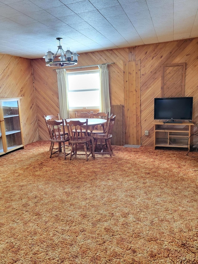 dining area featuring an inviting chandelier, wooden walls, and carpet