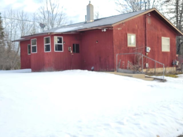 snow covered back of property with a chimney