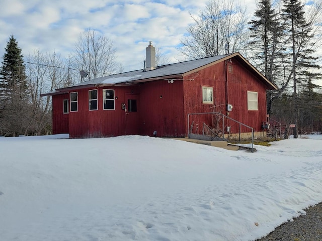 snow covered rear of property featuring a chimney