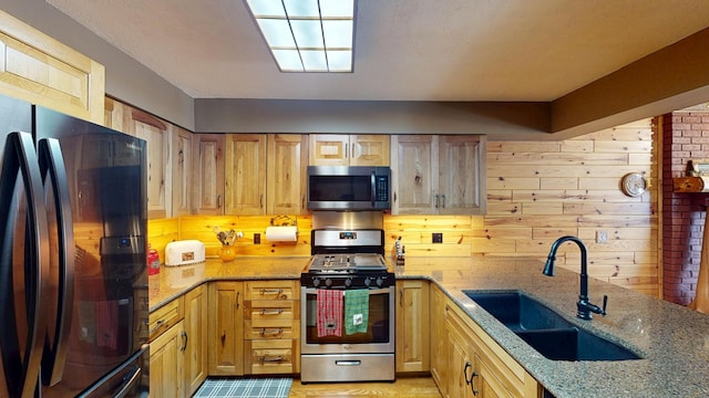 kitchen with a sink, light stone countertops, and appliances with stainless steel finishes