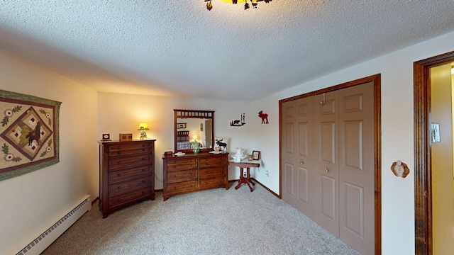 bedroom with a closet, light carpet, baseboard heating, and a textured ceiling