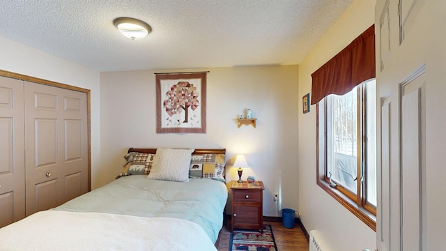 bedroom featuring a textured ceiling, wood finished floors, a closet, and a baseboard radiator