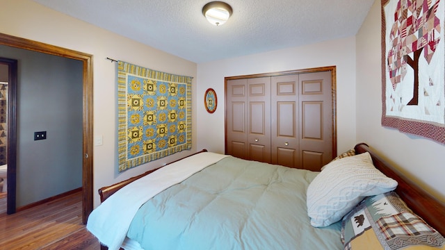 bedroom with wood finished floors, a closet, and a textured ceiling