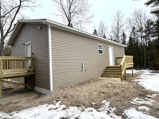 view of snowy exterior with a wooden deck