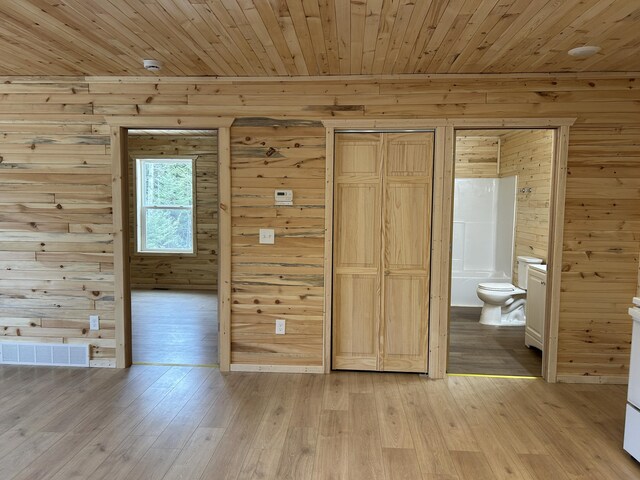 unfurnished bedroom with ensuite bath, wooden ceiling, light wood-style floors, and visible vents