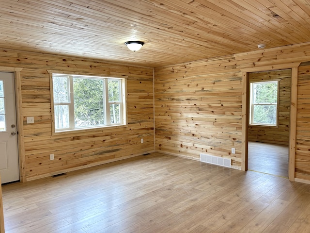 unfurnished room with a wealth of natural light, visible vents, light wood-style floors, and wooden ceiling