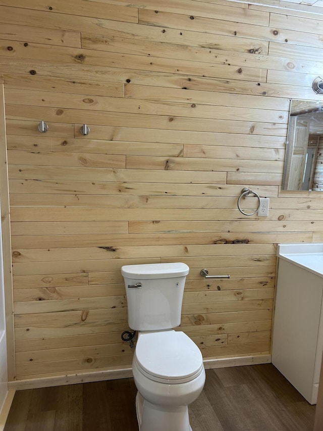 bathroom with vanity, toilet, wood finished floors, and baseboards