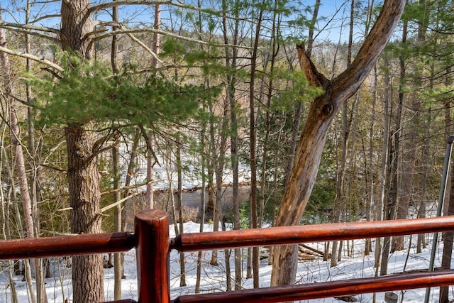 snow covered deck featuring a forest view