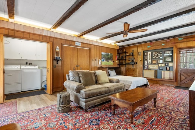 bedroom featuring beam ceiling, wooden walls, independent washer and dryer, and light wood-type flooring