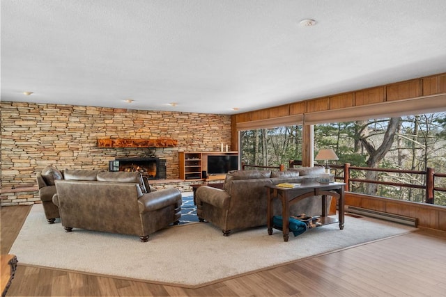 living room featuring wood finished floors, a fireplace, baseboard heating, and a textured ceiling