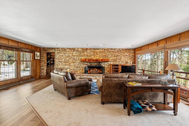 living area with a fireplace, wood finished floors, a healthy amount of sunlight, and wood walls