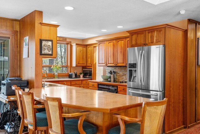 kitchen featuring backsplash, stainless steel appliances, a breakfast bar area, brown cabinetry, and light countertops