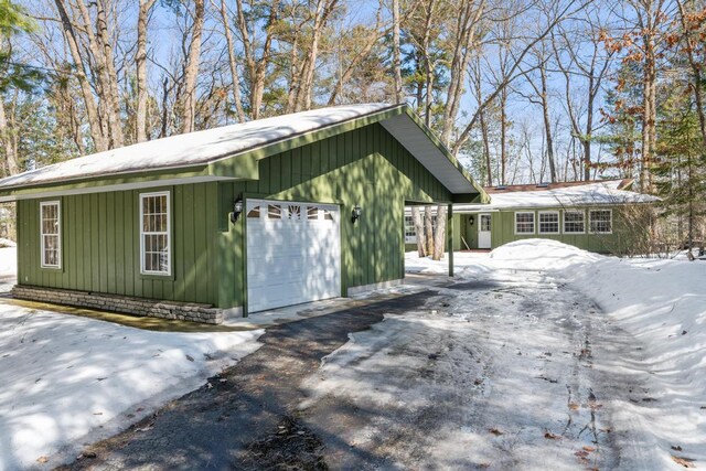 snow covered structure with an attached garage