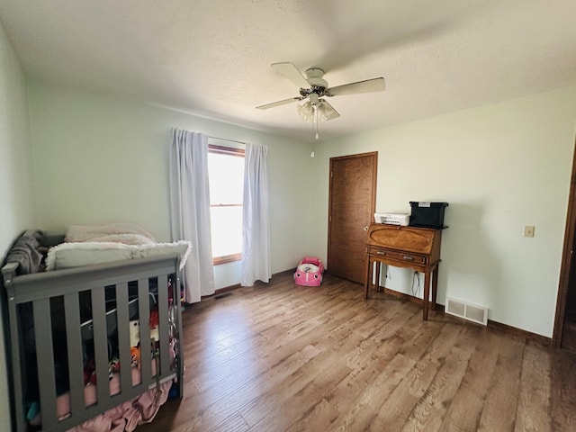 bedroom featuring visible vents, baseboards, ceiling fan, and wood finished floors