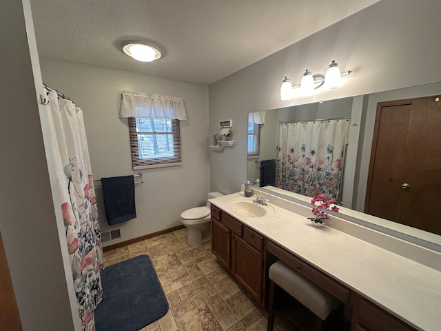 full bathroom with baseboards, toilet, vanity, stone finish floor, and a textured ceiling