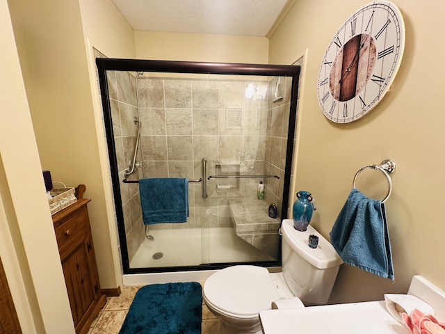 full bathroom with vanity, toilet, a shower stall, and a textured ceiling