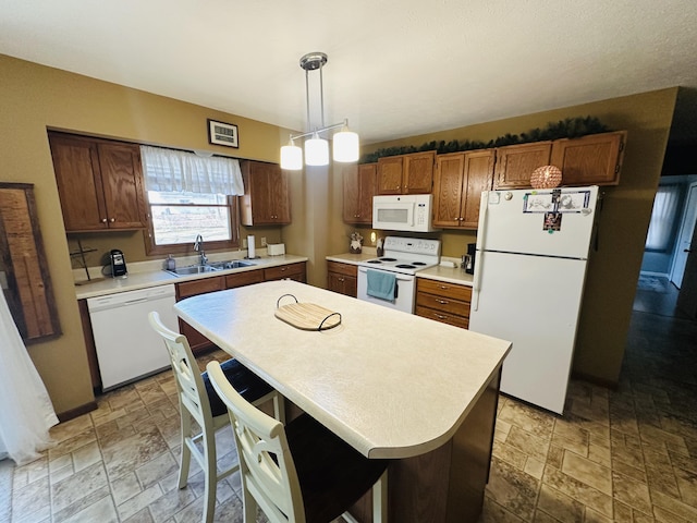 kitchen featuring white appliances, a sink, light countertops, stone finish floor, and decorative light fixtures