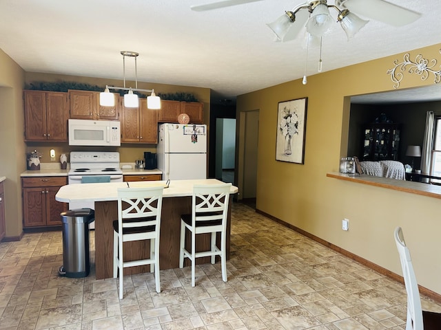 kitchen featuring white appliances, a ceiling fan, baseboards, a breakfast bar, and light countertops