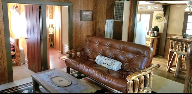 living room with wooden walls, wood finished floors, and ceiling fan