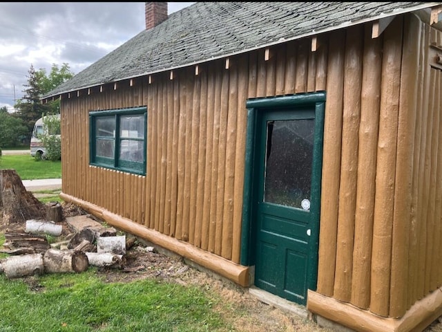 view of side of property with an outbuilding, board and batten siding, a chimney, and a shingled roof