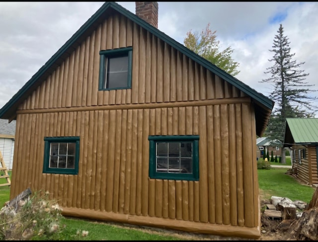 view of side of property featuring an outdoor structure, board and batten siding, and a chimney