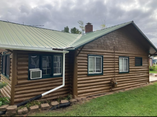 view of side of property with metal roof, log exterior, and a chimney