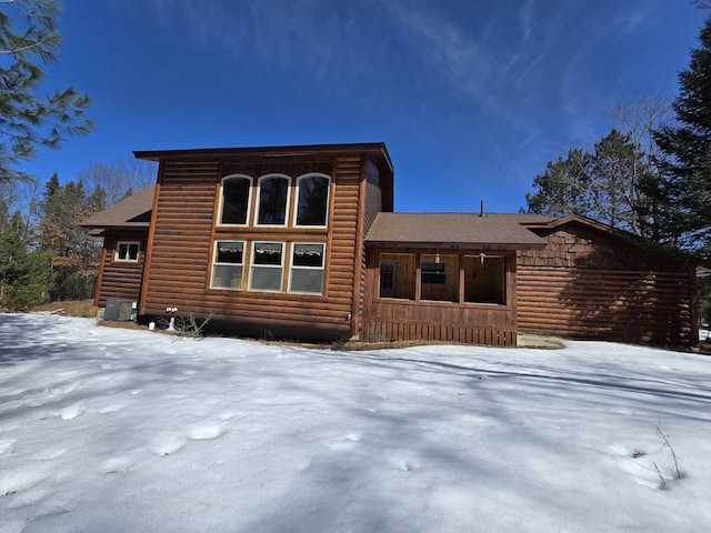 snow covered house with log veneer siding and roof with shingles