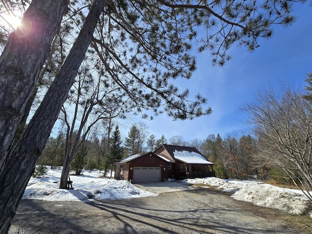 view of snow covered exterior with a garage and driveway