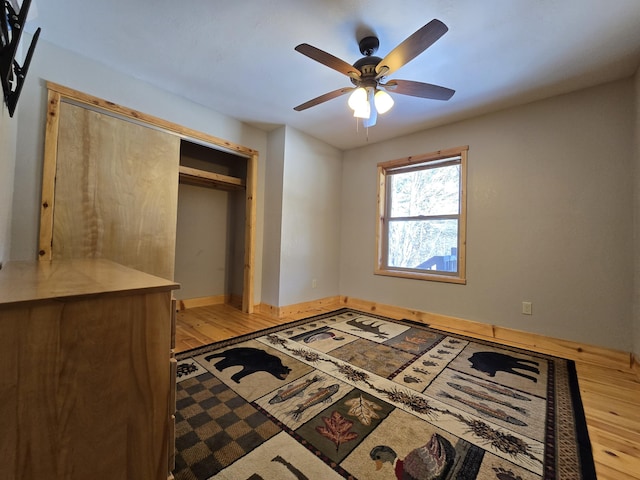 bedroom featuring a closet, light wood-style flooring, a ceiling fan, and baseboards