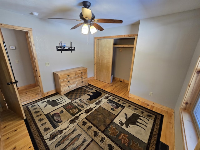 bedroom with light wood finished floors, ceiling fan, and a closet