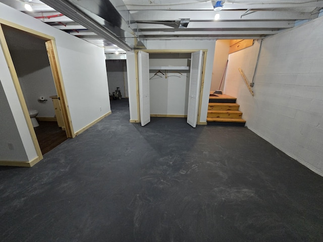 below grade area featuring concrete block wall, stairs, and baseboards