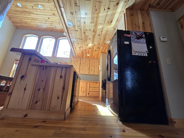 interior space featuring light wood-style flooring, wood ceiling, freestanding refrigerator, and lofted ceiling