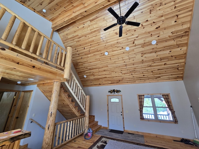 foyer entrance with wood finished floors, ceiling fan, stairs, wood ceiling, and a towering ceiling