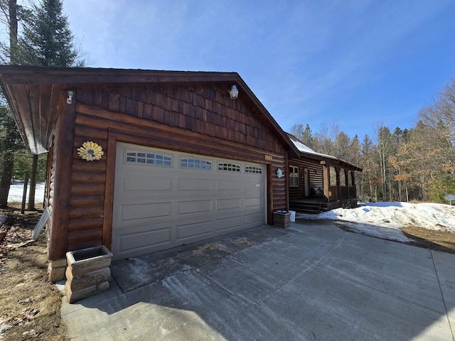 view of property exterior with faux log siding, a garage, and driveway