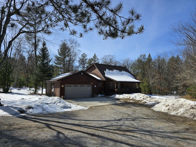 view of front facade featuring gravel driveway, faux log siding, and a garage