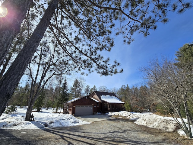 view of snow covered exterior featuring driveway and an attached garage