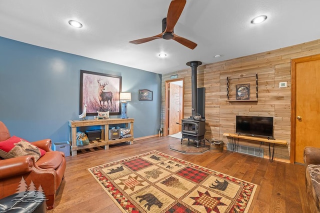 6122 Beach Rd, Johannesburg, MI 49751 - living room with ceiling fan, wooden walls, wood finished floors, and a wood stove