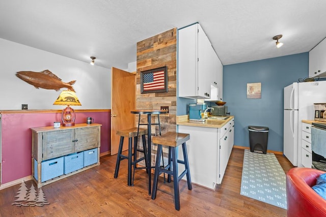 6122 Beach Rd, Johannesburg, MI 49751 - kitchen with light countertops, a sink, freestanding refrigerator, wood finished floors, and white cabinets
