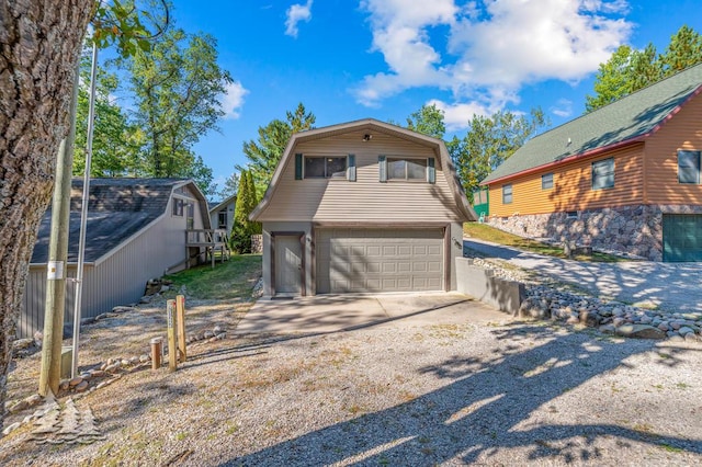 6122 Beach Rd, Johannesburg, MI 49751 - exterior space with gravel driveway, a gambrel roof, and an attached garage